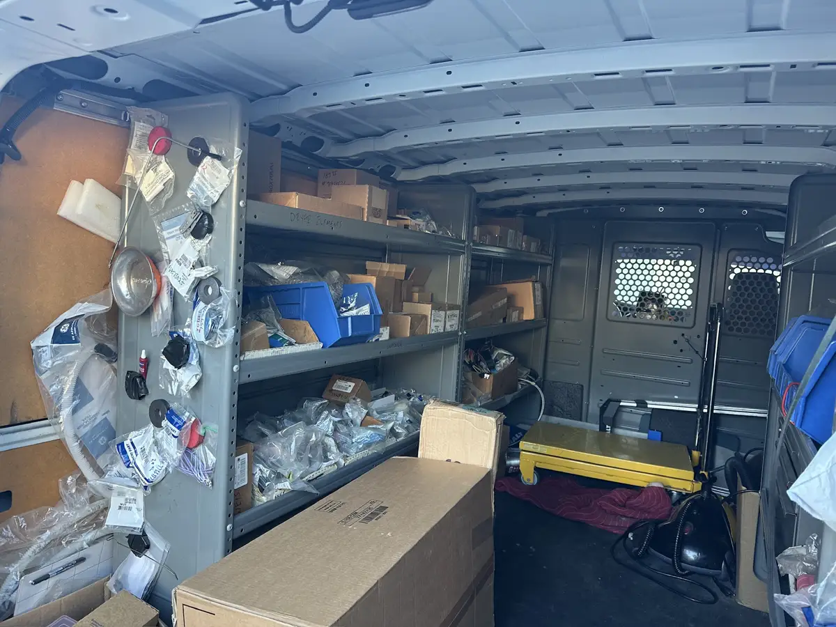 Shelves inside Brian's service van, stocked with boxed and bagged appliance parts
